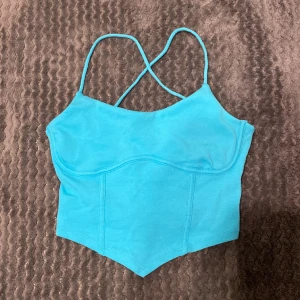Gina Topp - Jag säljer en topp från Gina Tricot i färgen blå/turkos. Banden är smala med kors i ryggen. Perfekt att ha på fest.