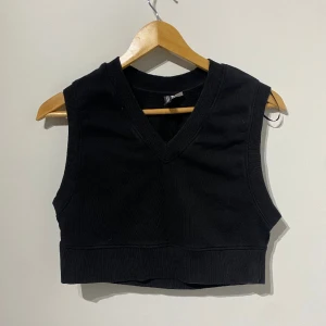 väst av tyg - en svart väst som nästan aldrig har används, den är croppad och sitter löst.