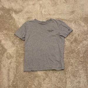 Grå t shirt  - Grå Calvin Klein T-shirt med två olika märken en på kanten och en på axeln