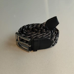 Flätat bälte  - Flätat bälte grå vit svart | stretch och anpassningsbar till alla storlekar | helt nytt aldrig använt | skriv om du har frågor.
