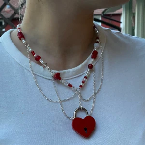 Egengjort hjärtlås layered halsband  - Halsband gjort av mig med glaspärlor, kedjor och ett hjärtlås! 43 cm långt och tyngre i fram pga låset. Aldrig använt.   Kan kompletteras med ett par örhängen med nycklarna tillhörande låset, hjärtan även de med! DM