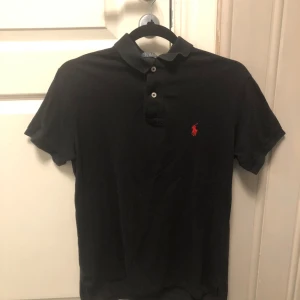 Ralph Lauren Piké Svart - Säljer nu min Raffe piké som jag växt ur. Den är andvänd och är ganska urtvättad samt ena lappen på insidan har ramlat av (se bild 3)❗️Storleken är S men sitter mer som XS 👏Om du har funderingar så hör av dig 🤝