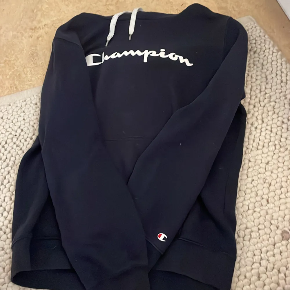 Mörkblå champion hoodie med text på bröstet. Hoodies.