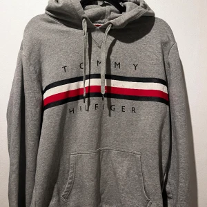 Tommy Hilfiger hoodie - En skitsnygg Tommy Hilfiger hoodie som är i bra skick förutom defekter längst ner på Hoodien därför det bra priset. Tveka inte att höra av dig vid frågor!