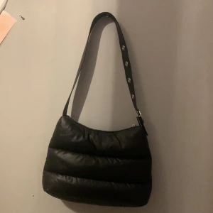 Handväska  - Handväska köpt på h&m det material den är på utsidan är samma som en jacka går att ändra längd! Mycket får plats i den och använd typ 5 gånger.