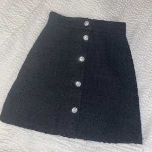 Kjol i bouclè - Supersöt kjol från H&M med knappar framtill och en dragkedja där bak. Stl 34 i bra skick. Säljer då den tyvärr inte passar mig längre 