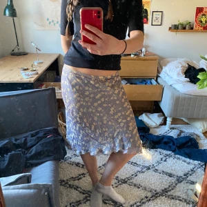 Lila kjol  - En lila kjol som är knälång på mig (175cm). Fint glansigt material med blommor på. 