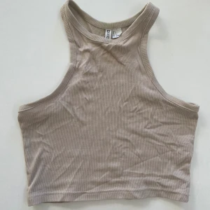DIVIDED ribbad tanktop (S) - En croppad, figurnära tanktop i ribbad bomullstrikå, storlek S. Toppen är smalt skuren upptill med brottarrygg🤍