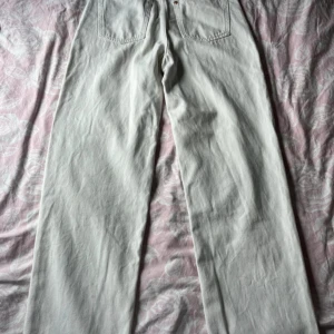 Vita jeansbyxor från A Denim - Ett par vita jeansbyxor från A Denim. Byxorna har en klassisk femficksdesign och är tillverkade i ett slitstarkt denimtyg.