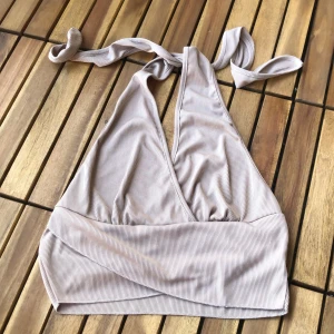 Beige halterneck topp från Shein - En beige halterneck topp från Shein i storlek L. Toppen är tillverkad av 80% polyester och 20% bomull, och har en ribbad struktur. Den har en omlott-design framtill och knyts i nacken.