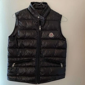 Moncler väst - Säljer nu min moncler väst pågrund av att den är för liten😃Den är i väldigt fint skick och knappt använd, Och ni kan även se hur den sitter på mig och jag är 162.