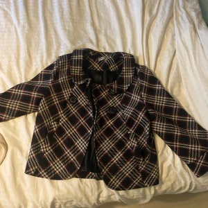 rutig jacka - en rutaktig jacka i storlek 38/40 med lite kortare armar som är utsvängda. Jackan har knappar och ett silkes material inuti som håller dig varm.