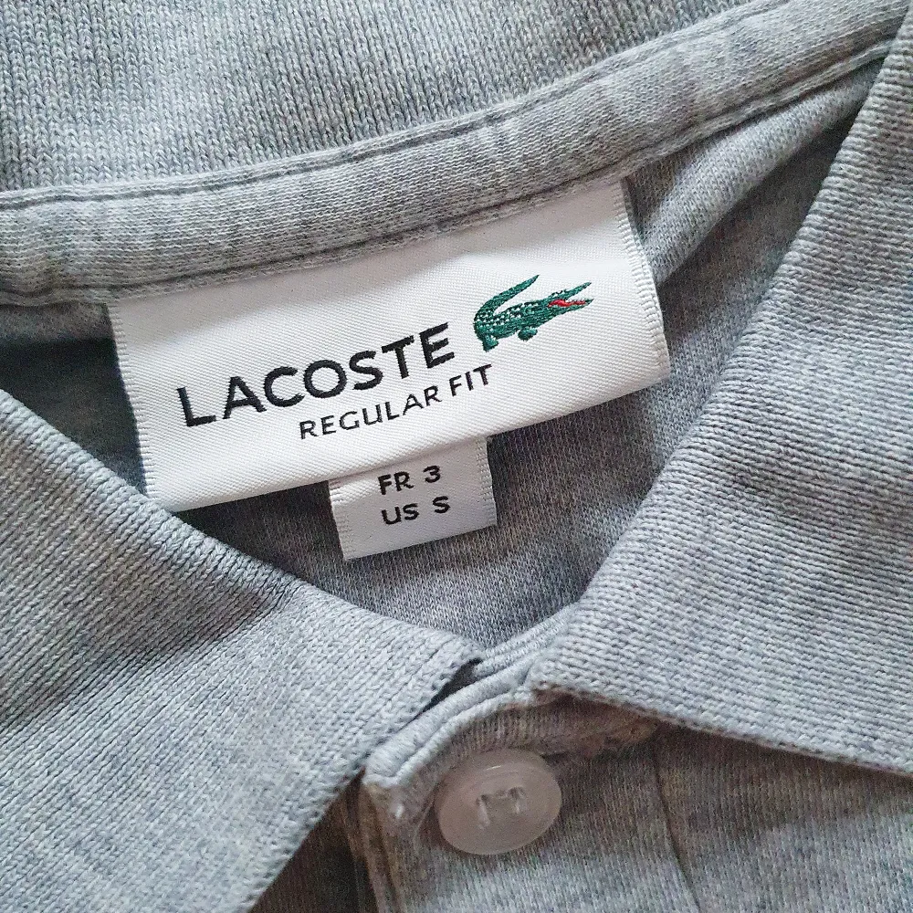 Nyskick! Riktigt fin Lacoste Pikétröja L1264 - Gråmelange Använd max 5 gånger så är som ny fortfarande och nu när man blivit rundare runt magen så passar den inte längre på mig.. T-shirts.