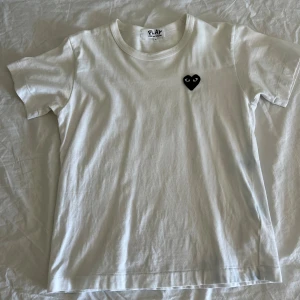Vit cdg play t-shirt - Vit bomulls t-shirt från cdg play (comme des garcons) som är i storlek L men sitter som en S. Vanlig passform utöver det och skön och fin nu till sommaren. Bra skick, använd ett fåtal gånger