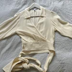 Omlottblus - Jättefin omlottblus i krämvit som man knyter i midjan, använd en gång så är som ny! Köpt från other stories, nypris 700-800 kr.