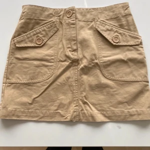 Kort kjol beige strl 34  - Fin beige kjol i beige  Från H&M  Aldrig använd  Med knappar vid ficka 