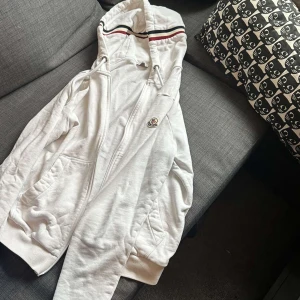 Moncler zip hoodie - Tja, säljer nu denna vita Moncler zip hoddie i topp skick utan defekter. Vill sälja den då den inte riktigt kommer till andvändning längre.