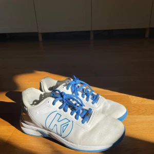 Kempa skor - Säljer dessa blå och vita handboll skor i bra skick. Skorna är i storlek 39 och ena skorn har en skada längst bak.