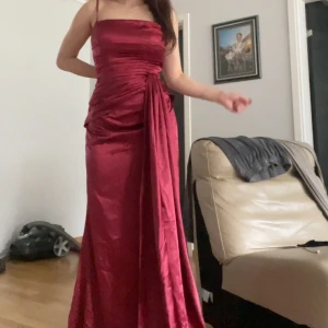 Balklänning - En vin röd balklänning, storlek M dock kan den passa lite större S storlekar. Den är vintage från min mammas gamla bal men bara använd en gång. Jag är 170 cm lång och den är ganska lång så den passar bra med klackar. Priset kan diskuteras.
