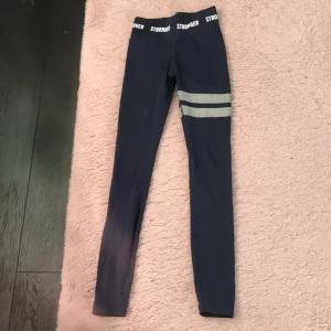 Träningsbyxor STRONGER - Träningsbyxa från stronger, köpa för 799kr. Jättebra skick förutom slitage som syns på andra bilden. Skulle säga att den är ganska liten i storleken och smal i midjan och ben. Jag tror att den skulle passa någon från 130-150. Skriv för fler bilder.💕💓