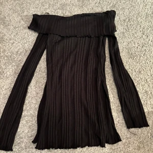 En svart topp från Gina Tricot  - Toppen har slit samt slit i slutet av armarna också. Toppen är off the shoulder.