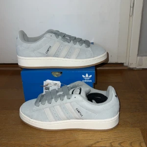 Adidas campus 00s ljusblåa - Oanvända  - Hej alla skoälskare! Säljer ett par oanvända ljusblåa Adidas Campus i storlek 39 1/3. Dessa trendiga (slutsålda) och bekväma skor är inköpta från JD Sports. Svarta snören ingår.Finns i Örebro för upphämtning, men kan även skicka dem till dig (118 kr)