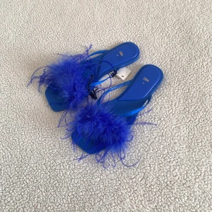 ZARA blåa sandaler med strutsfjädrar  - Otroligt snygga sandaler med strutsfjädrar från ZARA. Nya med tags kvar, utan anmärkningar. 