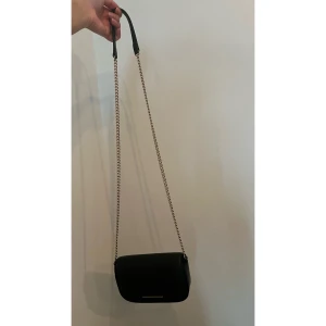 Axelremsväska i kedjan - H&M - Säljs en jätte fin söt liten axelremsväska. Den var köpt från H&M. Har ej hunnit använda den och dags att rensa min garderob. Väskan är 18x12 cm