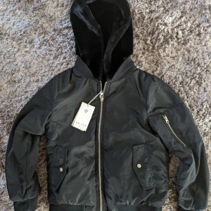 Vändbar bomberjacka - Svart oanvänd vår- och höstjacka. Fickor på båda sidor. Märke: Ricano