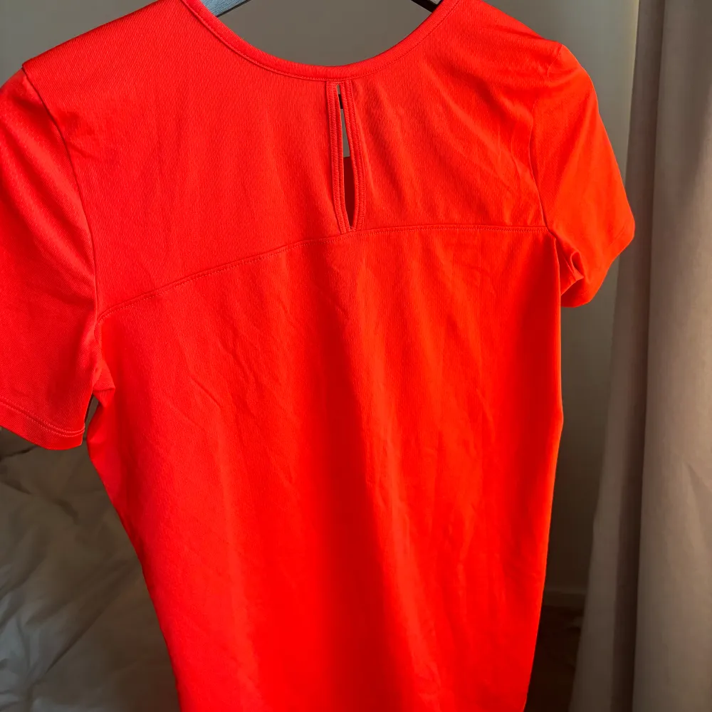 Nyskick. Funktions t-shirt från under armour i aprikos/orange-röd fin färg.. Sport & träning.