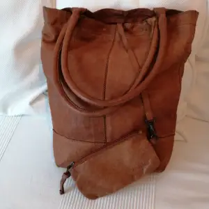 Superfin skinnväska.  Väska i läder som knappt är använd. Väskan stängs med en dragkedja. Liten plånbok / förvaringsväska medföljer 10 x 17 cm. 