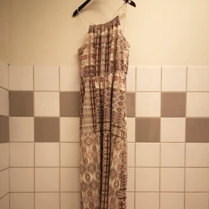 Stilig långklänning - Underbar klänning med slits, knappt använd. Jag är lite för kort (160cm), snygg med skinnjacka en kall sommarkvälll. Stl XS/S Färg: Benvit med mönster