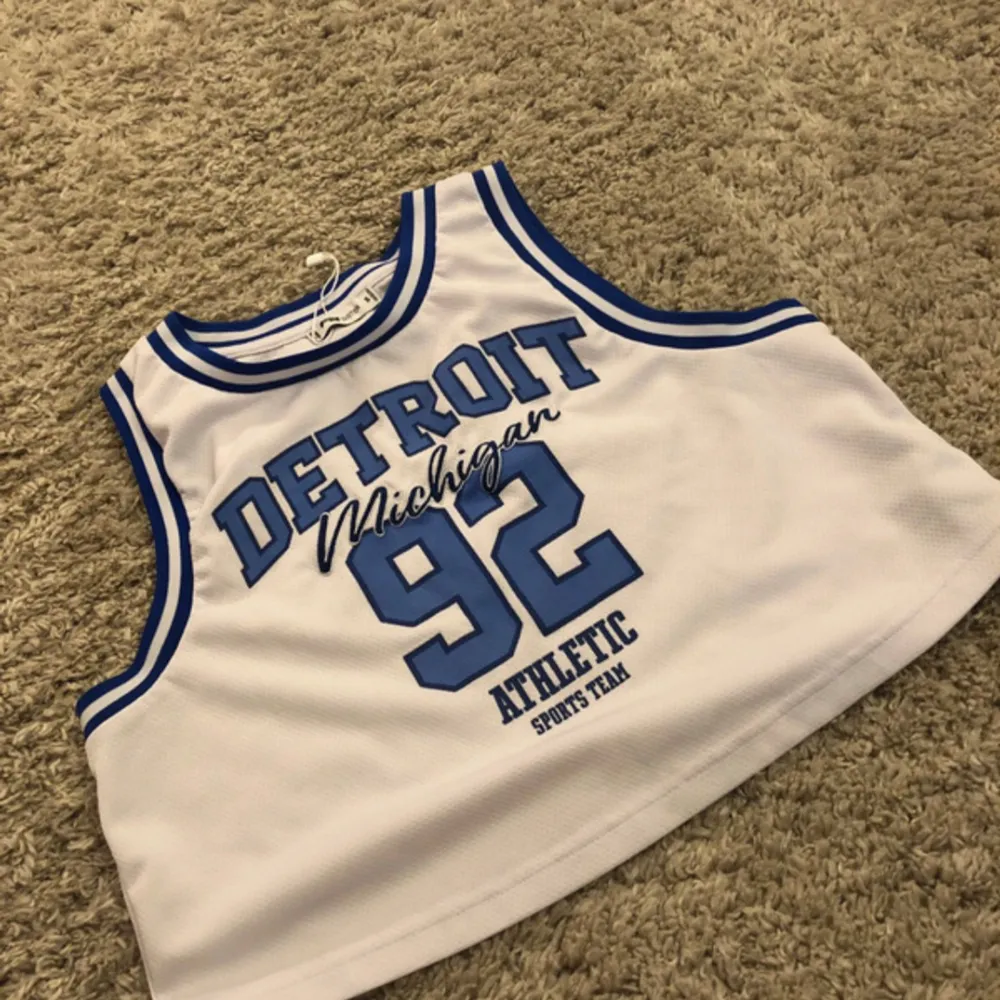 White basketball top with blue text. Toppar.