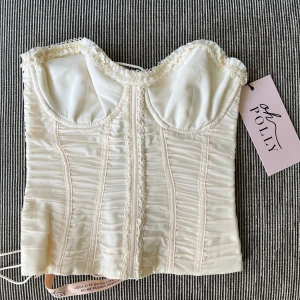 Helt oanvänd OhPolly korsett/topp - Helt oanvänd ohpolly topp/korsett i storlek 4 (a-c) - motsvarar xxs.  Färg: Ivory Supersnygg festtopp men tyvärr var den för stor upptill för mig.  