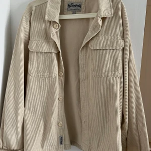 Skjortjacka - Pullover eller skjortjacka i ljusbeige. Storlek M herr. Väldigt sparsamt använd 