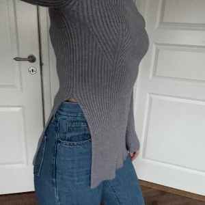 NAKD ribbad tröja med slits  - En grå ribbad tröja med slits vid sidorna, ger en smickrande form. Storlek S, legit aldrig fått användning för den så så gott som ny. Nypris 439 kr.