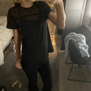 SVART T-shirt med detaljer  - Den är svart men tog med den vita för att man bättre skulle se mönster! Fin svart T-shirt med fina detaljer runt halsen. Andvänd ca 3 ggr och har Inga tecken på andvändning! Pris kan diskuteras