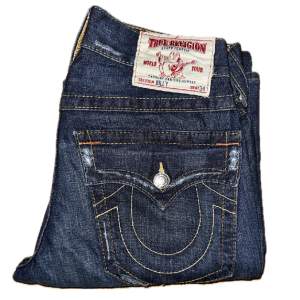 Tvärfeta True Religion jeans i modellen av Billy. Köpt från BenimDenim men måste tyvärr sälja eftersom de inte passar mig. Storlek 30/34. Midja: 39 cm. Yttersömm: 110 cm. Benöppning: 24,5 cm. Vänligen ställ frågor. Priset kan diskuteras.