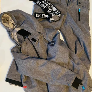 Skidställ  - Grått ställ för vintersport/lek. Byxor, jacka, luva och hängslen. Obetydligt använt. Hämtas, Gamla Råslätt, endast swishbetalning