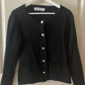 Kofta - Svart kofta med knappar i mitten. 