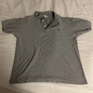 Lacoste piké  - Säljer en Lacoste pike i storlek S. Knappt använd, i grå.