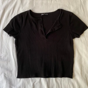 Svart croptop från Zara - Superfin liten svart, ribbat t-shirt från Zara. Är en S men är liten i passformen