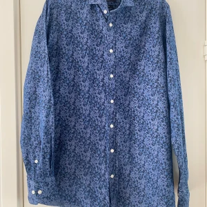 Marinblå mönstrad skjorta från Bruun & Stengade i strl 38 - Marinblå mönstrad skjorta från Bruun & Stengade i strl 38.  Sparsamt använd och i fint begagnat skick.  Mått Över bröstet: ca 52 cm Längd från axeln och ner: ca 74 cm