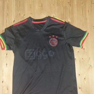 Ajax bob marley kit - Riktigt snygg fotbollströja, lager är ajax och tadic som spelare på ryggen. Den här tröjan vill många som spelar fotboll ha eftersom den är så snygg därför säljer jag den för bara 350kr! 