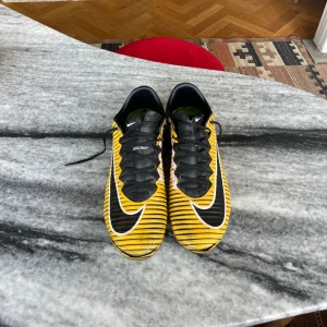 NIKE Mercurial Vapor XI ”Laser Orange” FG ACC  - Ett par av den (enligt min mening) bästa fotbollskomodellen som någonsin gjorts. Använda men i fullt spelbart skick. Minimal slitning vid toeboxen. Namnteckning (går att skrapa bort/stryka över). Mycket svåra att hitta, såldes för 8 år sedan.