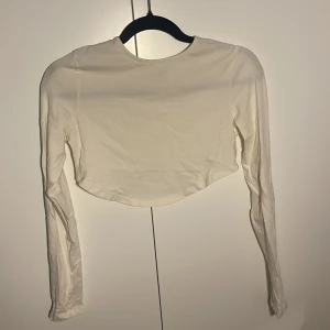 Topp - Liten rundning och längre där framme (fortfarande magtröja) och kortare där bak. Från Nelly, deras egna märke. Fin skick. Ganska tunn och man kan se igenom litegrann, funka med vit bh.