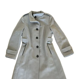 Lång Grå Kappa - Kappan är grå men lite åt beige hållet, den är i mycket bra skick och är knappt använd. Kappan är också i ett väldigt lyxigt och mysigt material. Skriv gärna för att se mer bilder eller om ni har några frågor! Skriv också innan ni använder ’köp nu’ 🤍