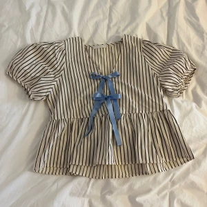 Randig blus med puffärm - Randig topp med puffärmar och silkesband med rosetter. Ganni-inspirerad. Extremt fin! Jag har bytt ut originalbanden mot blå silkesband för att ge den ett lyft 😍