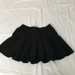 Svart veckad kjol  - Svart veckad kjol från Shein Skick: Godtagbar skick Material: 95% polyester 5% spandex  Förslutning: Dragkedja  Mönster: Inget Detalj: lite luddig, ganska kort Finns det frågor är det bara att skriva! 💕💕 