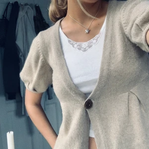 Kofta med korta ärmar  - Glittrig beige kofta med korta puffärmar  